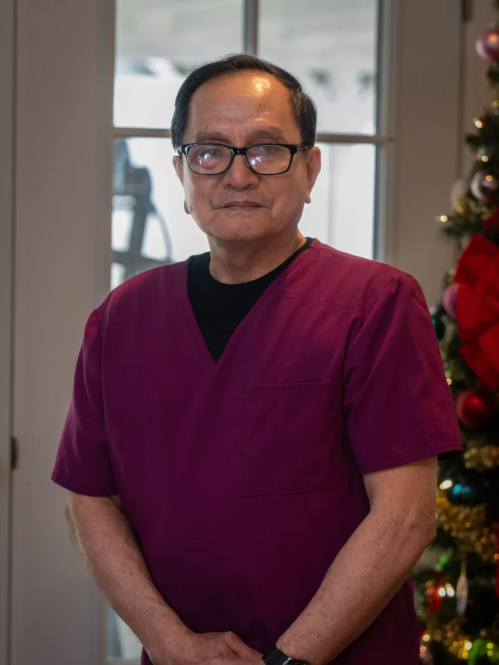 Healthcare professional in burgundy scrubs standing in facility common area